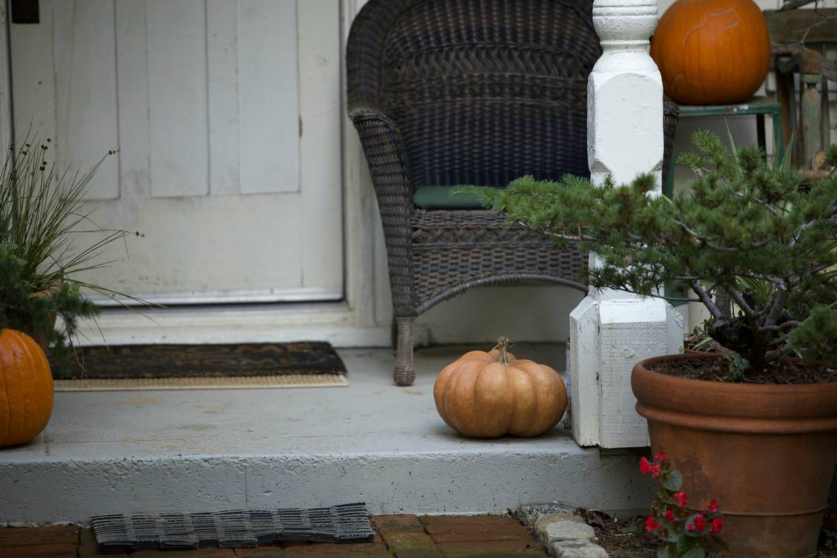 Stylish home for christmas doormat on snowy porch with wreath and potted evergreens