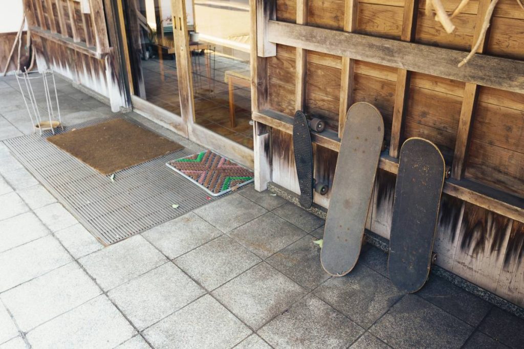Two skateboards lean against a wooden wall.